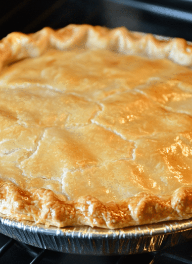 A freshly baked chicken pot pie with a golden crust, creamy filling, and colorful vegetables on a rustic wooden table