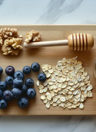 Wooden cutting board with rolled oats, blueberries, walnuts, honey, almond milk, and cinnamon.